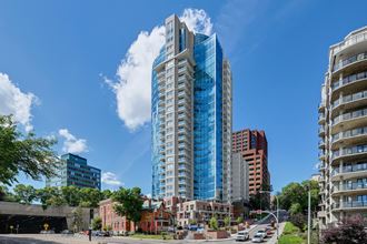 a tall blue skyscraper on a city street with other tall buildings