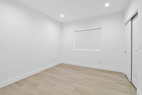 A white room with a wooden floor and a white door.