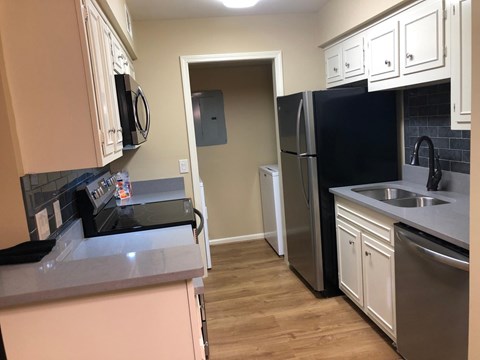 A kitchen with black appliances and white cabinets.