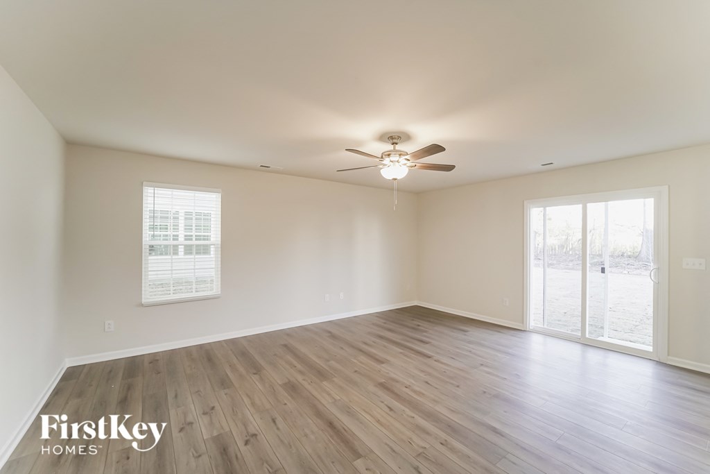 an empty living room with wood floors and a ceiling fan