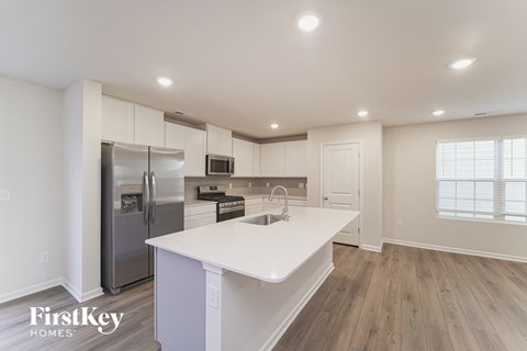 a white kitchen with a white counter top and a stainless steel refrigerator