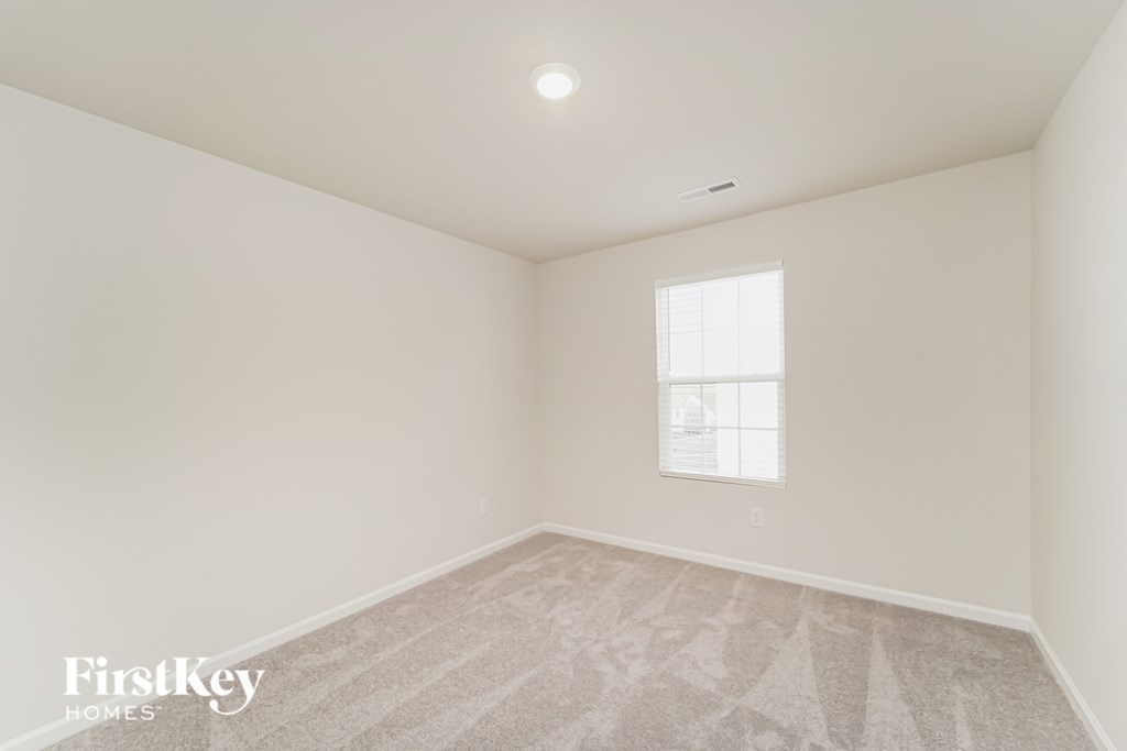 a bedroom with white walls and carpet and a window