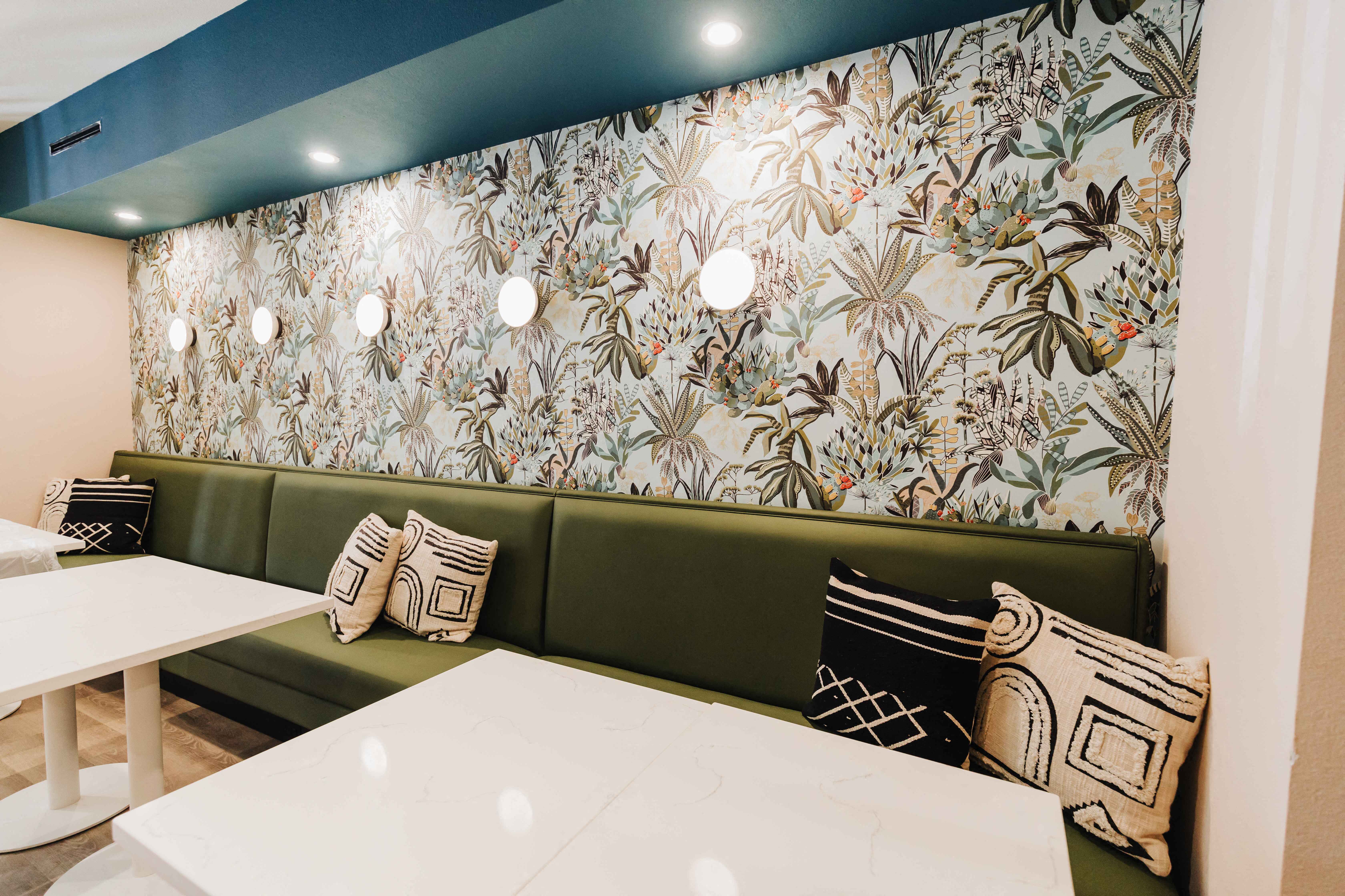 a dining room with green couches and pillows and a table