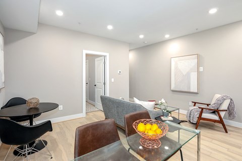 a living room with a glass table with a bowl of fruit on it