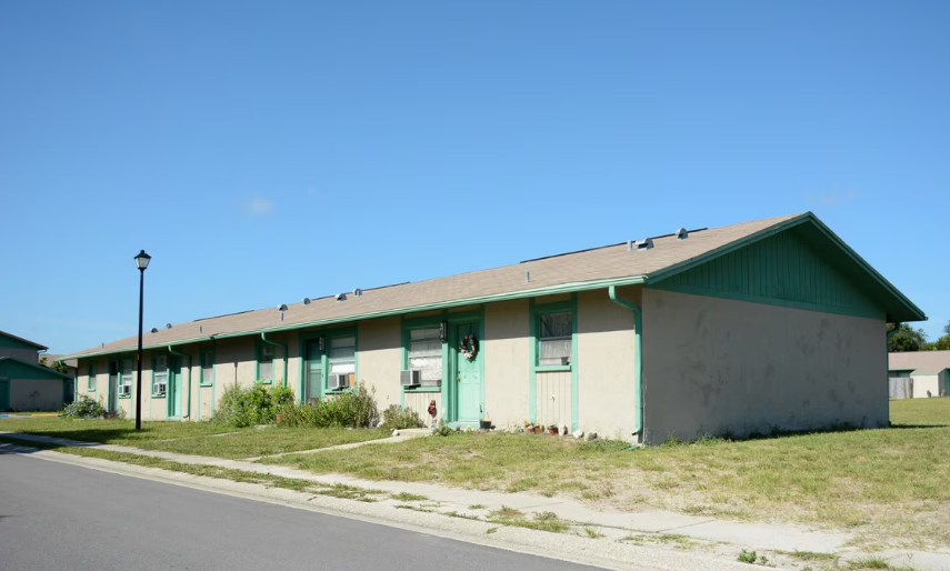A green and white building with a green roof and a street light in front.