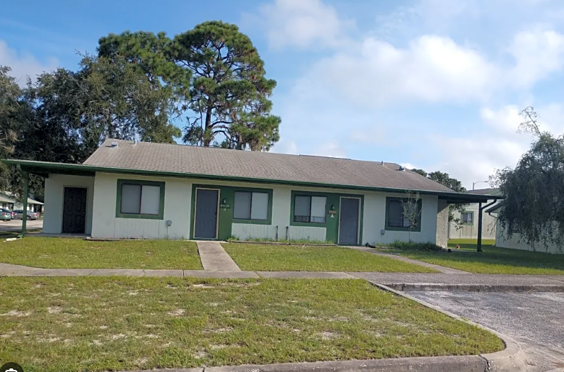 A small building with a green door and a grey roof.