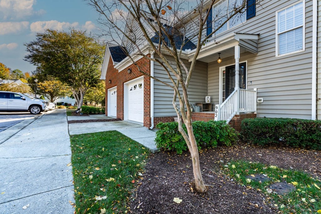a house with a sidewalk and a tree in front of it