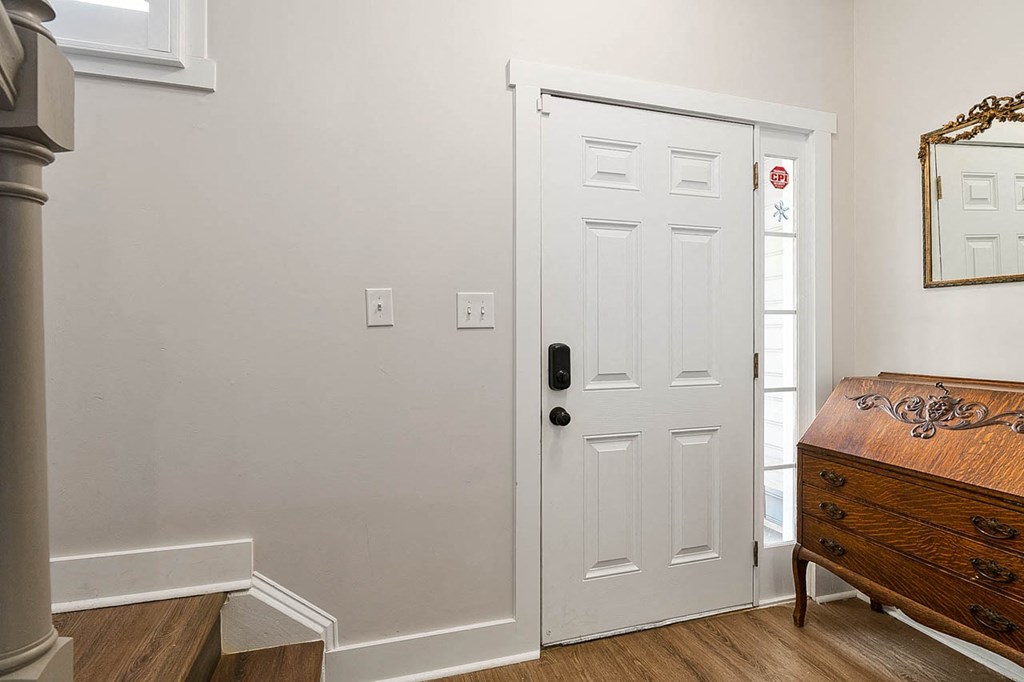 a bedroom with a white door and a dresser next to it
