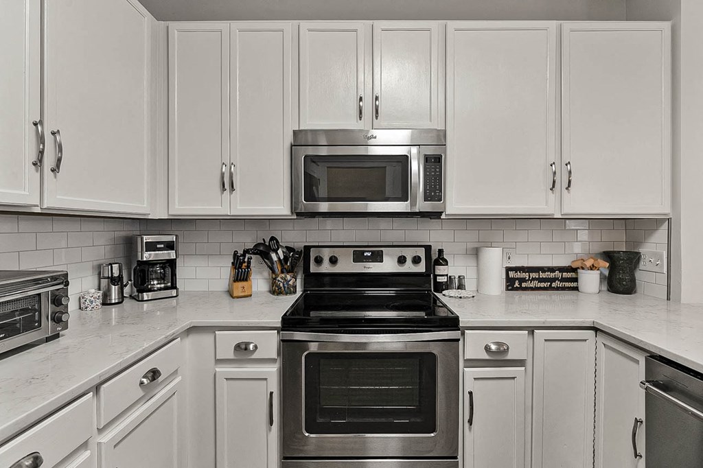 a white kitchen with stainless steel appliances and white cabinets