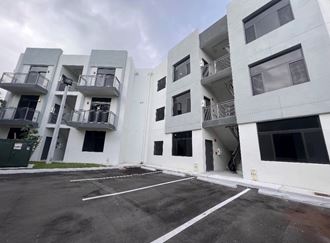 the exterior of a white apartment building with empty parking lot