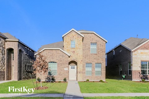 side view of two story brick home with green grass and a blue sky