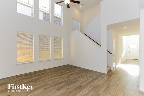 an empty living room with white walls and wood floors and a ceiling fan