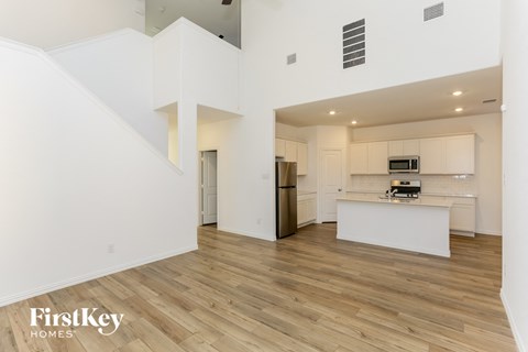 a living room and kitchen with white walls and wood flooring