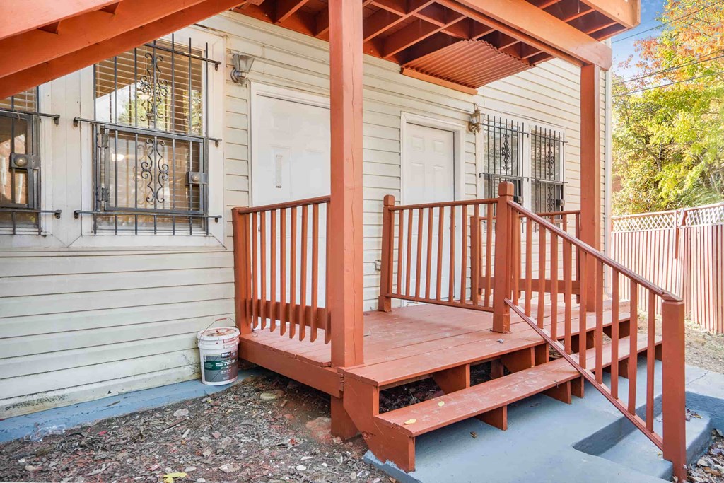 a front porch with a red railing and a porch swing