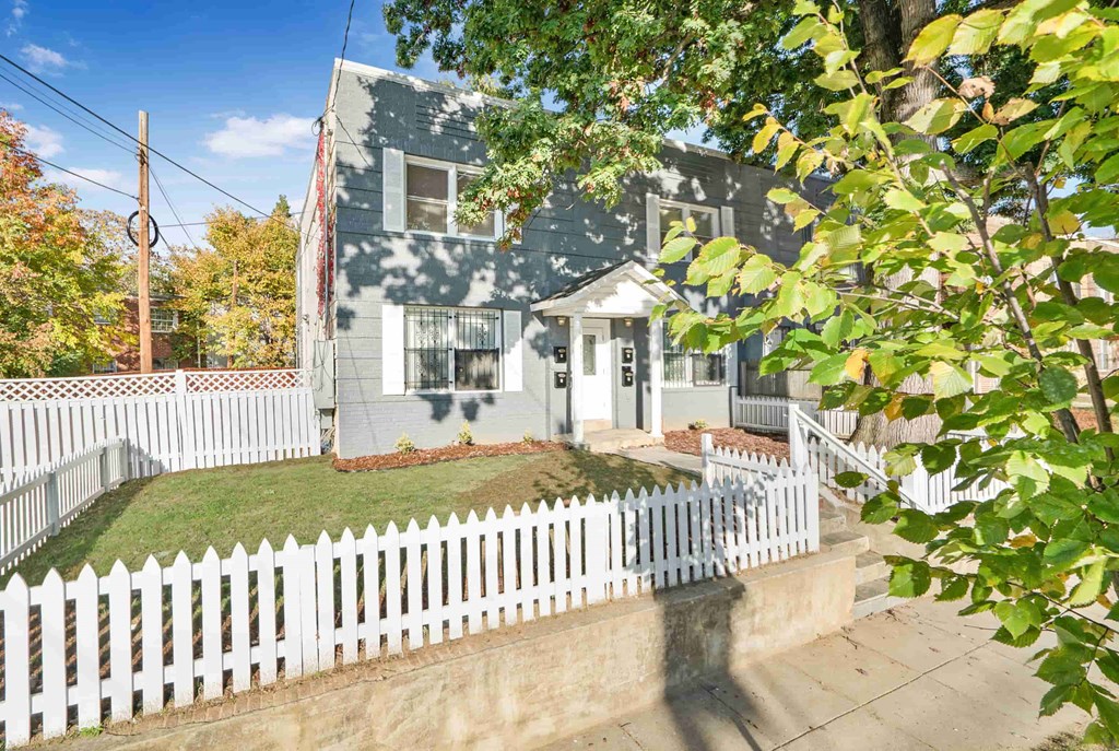a blue house with a white fence in front of it