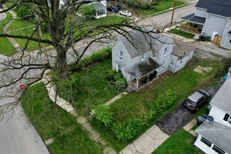 an aerial view of a white house with a tree in the yard