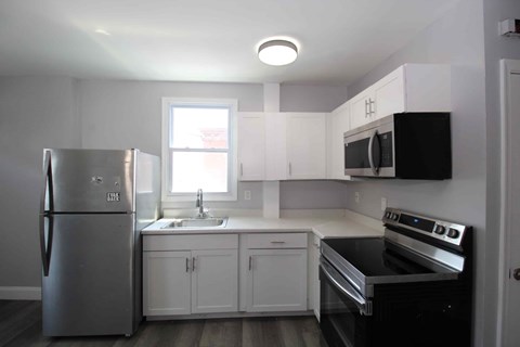 A kitchen with a stainless steel refrigerator and black stove top oven.
