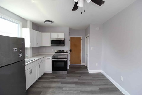 A kitchen with white cabinets and a black fridge.