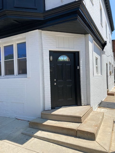 A black door is on the front of a white house.