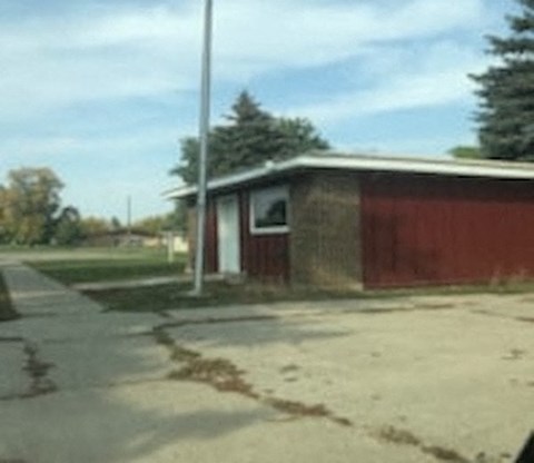 a small building with a red fence next to a street