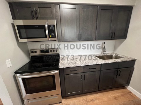 a kitchen with dark cabinets and a sink and a microwave