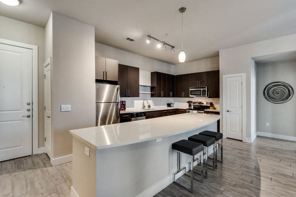 a kitchen with a large island and a stainless steel refrigerator