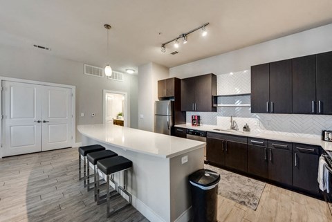 a kitchen with a white counter top and dark cabinets