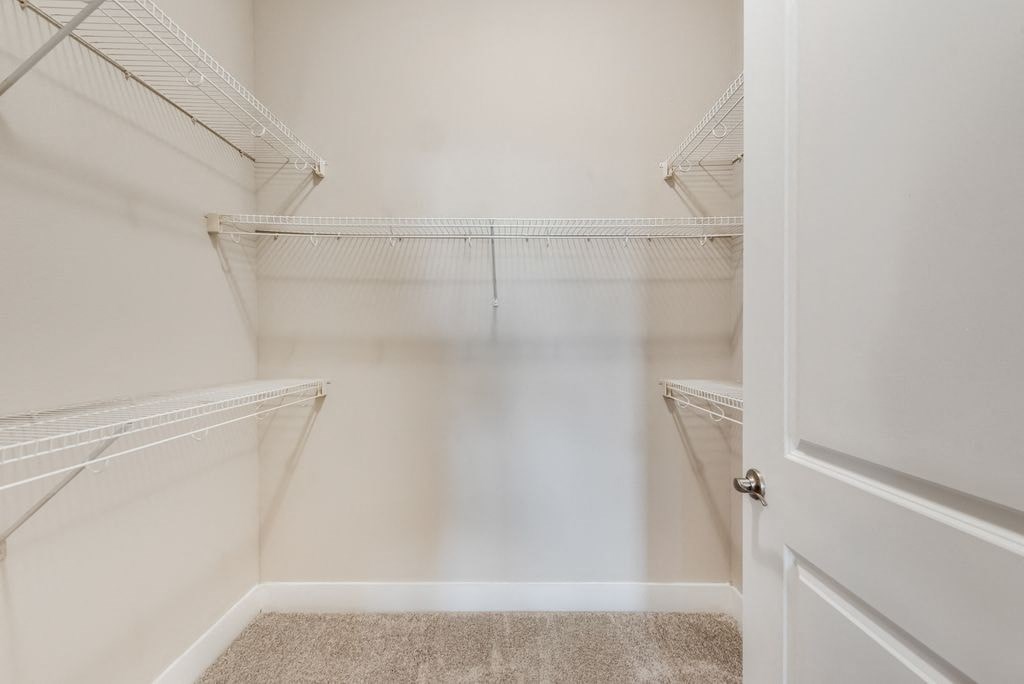 a walk in closet with empty shelves and a door