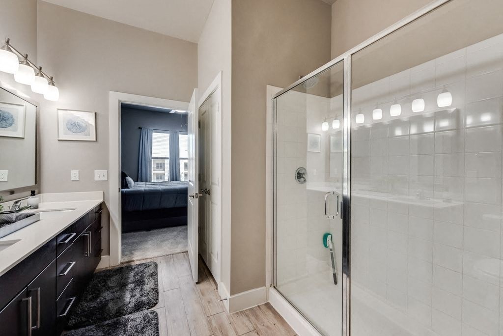 a bathroom with a glass shower and a door to a bedroom