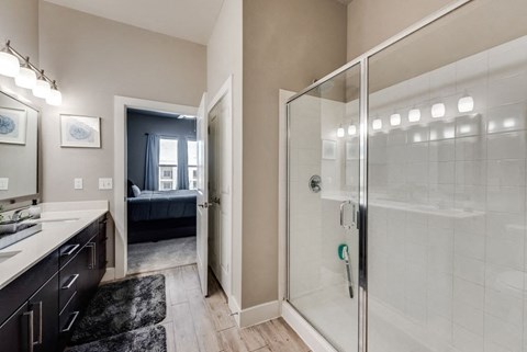 a bathroom with a glass shower and a door to a bedroom