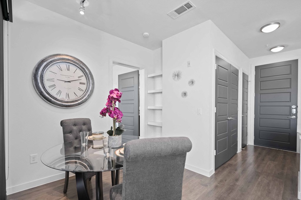 a dining room with a glass table and a clock on the wall