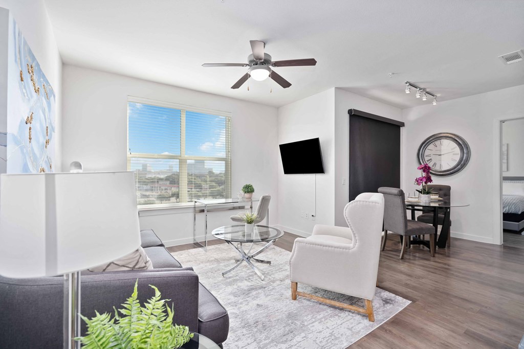 a living room with white walls and a ceiling fan
