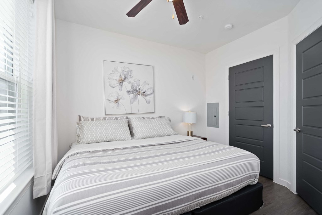 a white bedroom with a bed and a ceiling fan