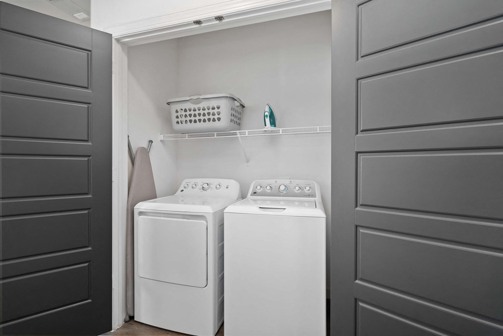 a small laundry room with white appliances and black doors