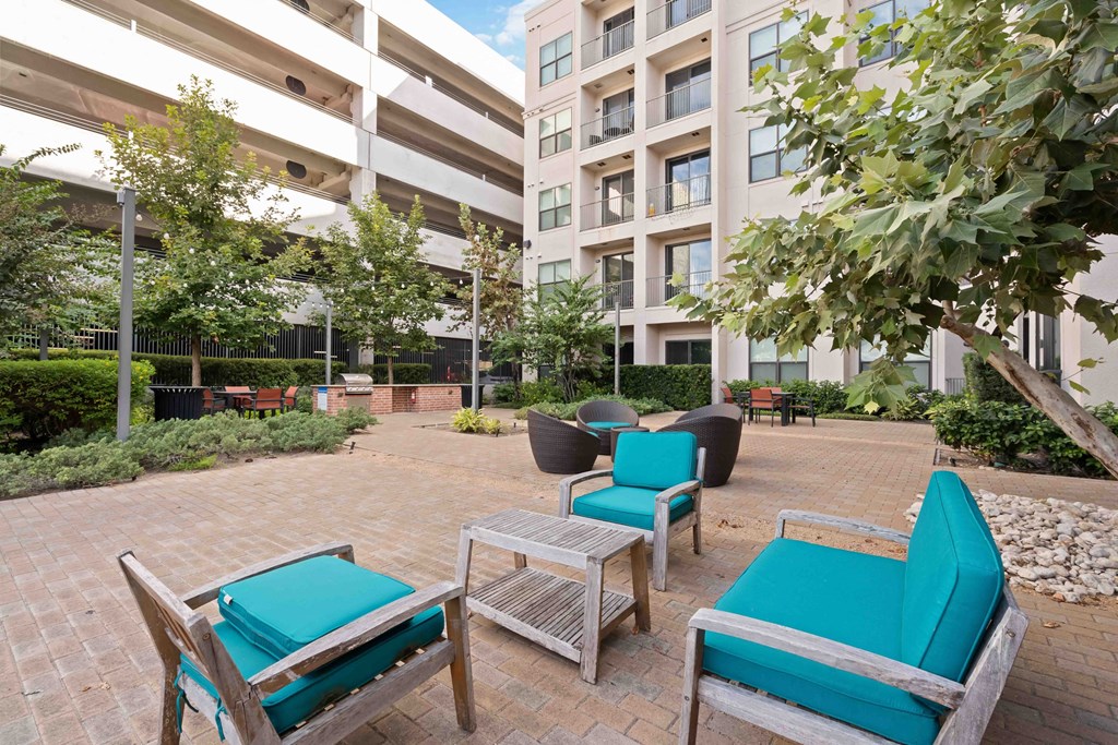 a patio with chairs and a table in front of an apartment building