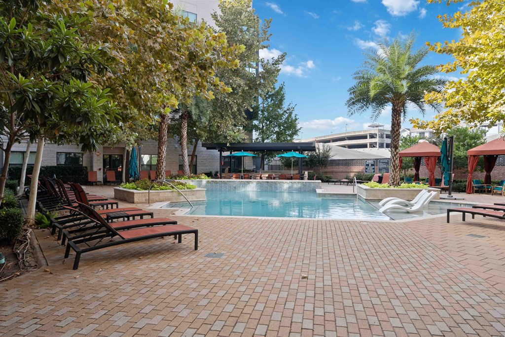 a swimming pool with benches and trees and a building in the background