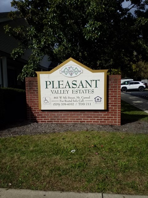 a sign for pleasant valley estates in front of a brick wall