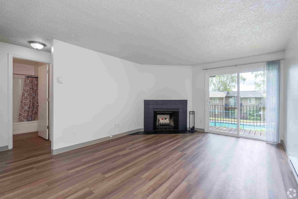 an empty living room with a fireplace and wooden floors