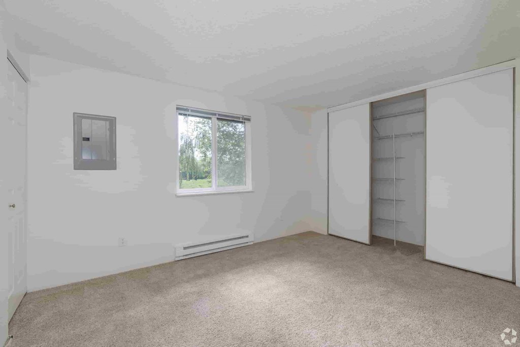 an empty bedroom with white walls and a door to a closet