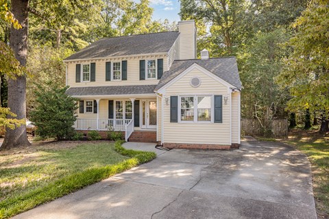 A house with a white front porch and green shutters.