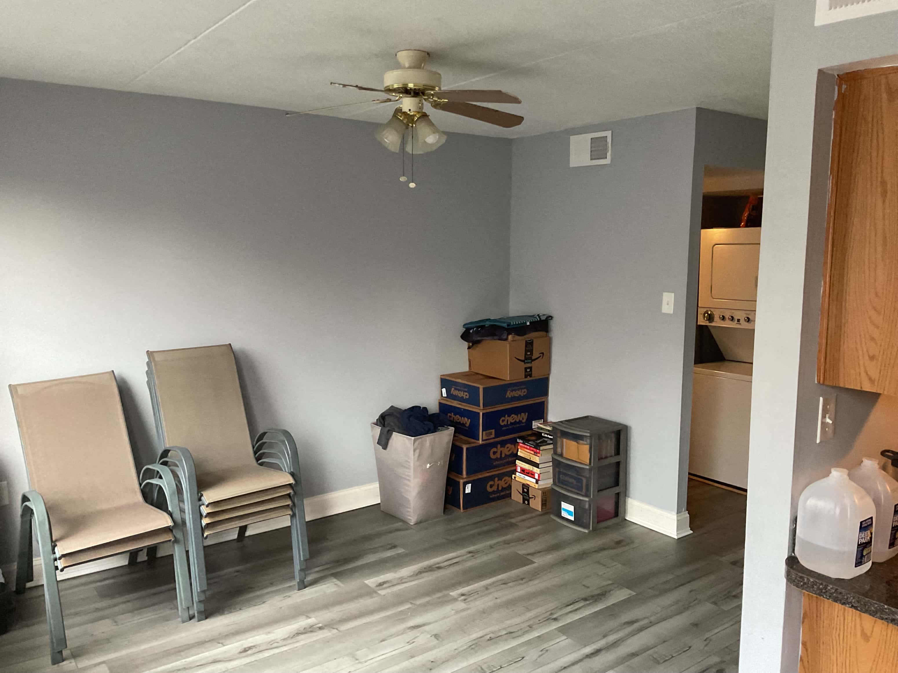 a room with two chairs and boxes on the floor and a ceiling fan