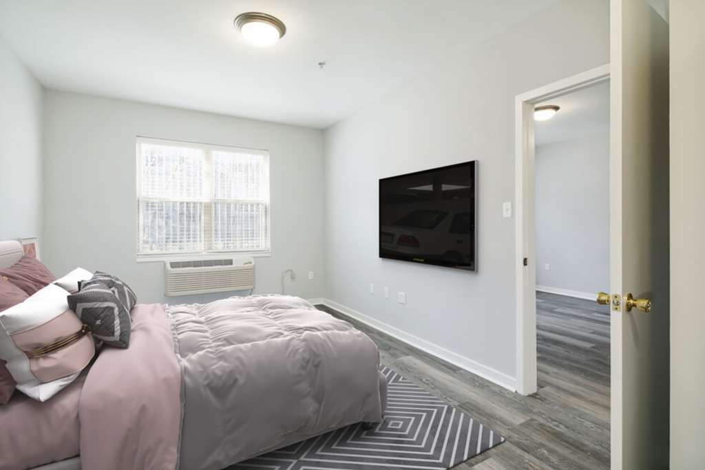 a bedroom with a bed and a tv on the wall