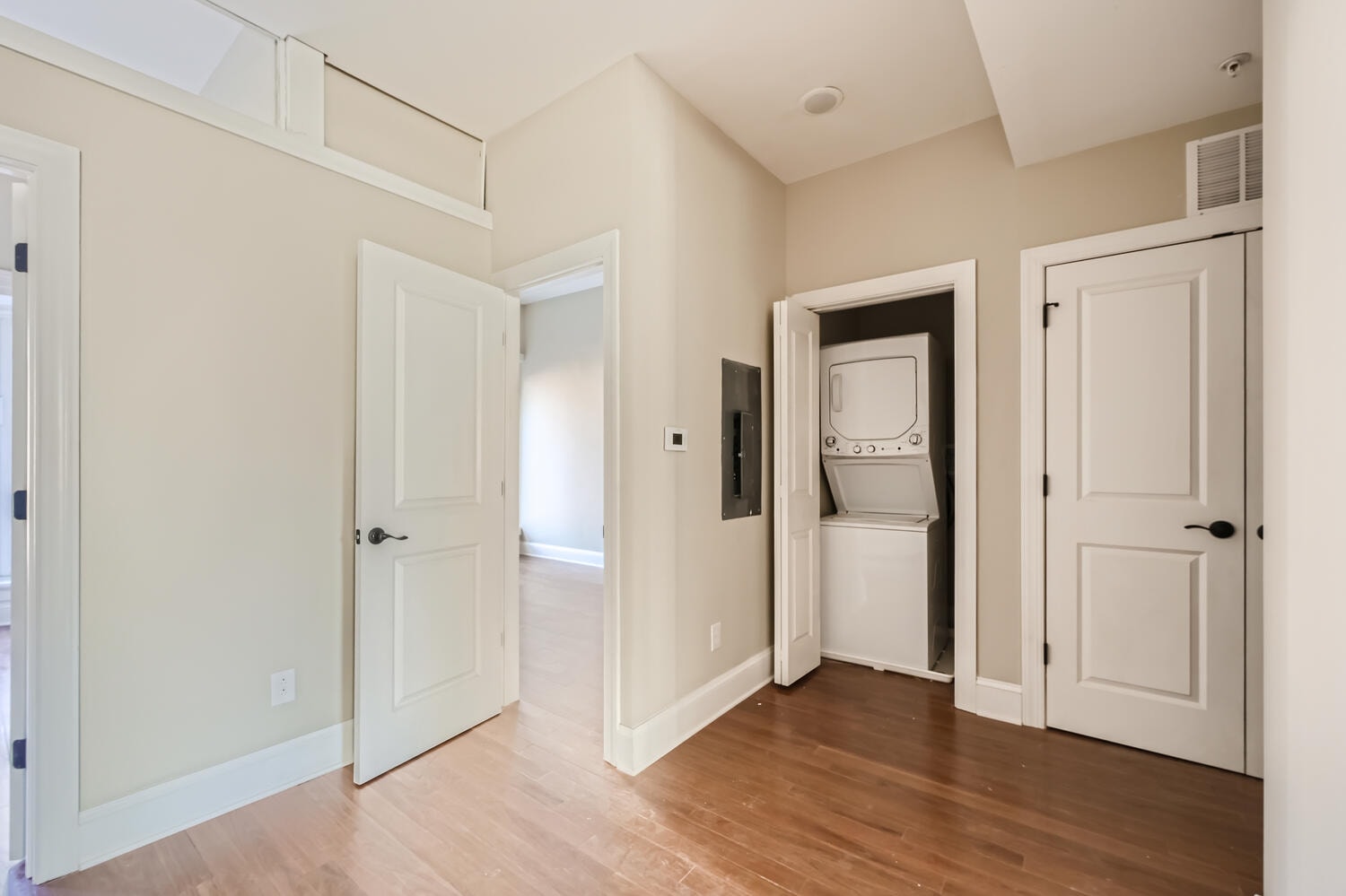A room with a white door and a white fridge.