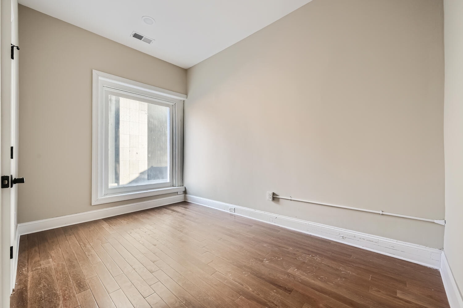 A room with a window and wooden flooring.