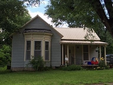 a small white house with a yard and a tree