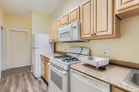 A kitchen with a white stove top oven and a white microwave above it.