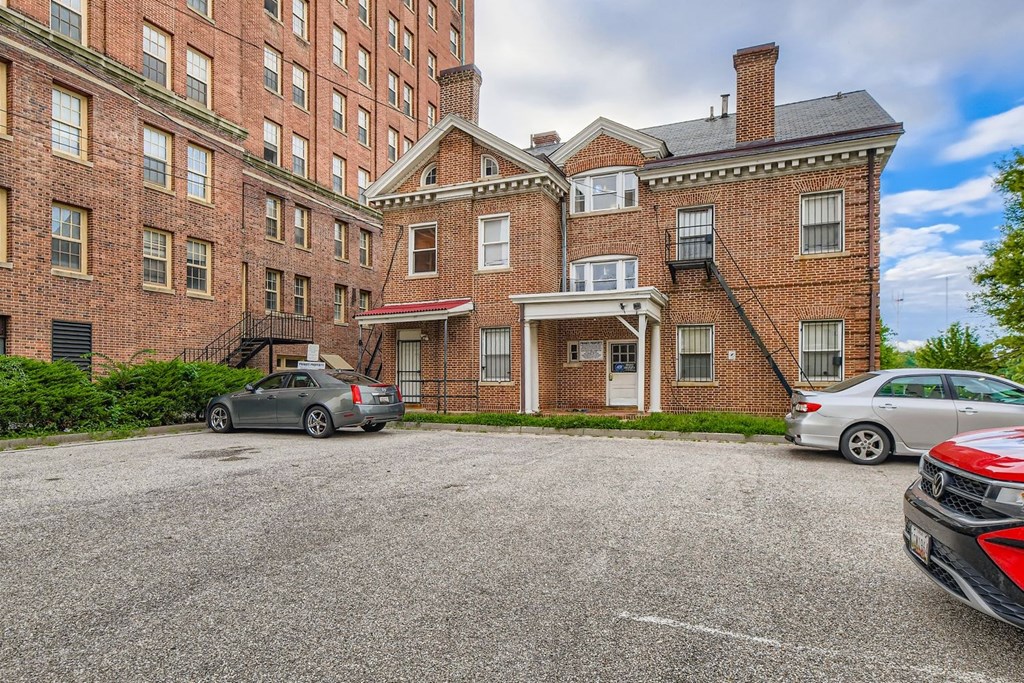 A parking lot with cars and a red brick building.