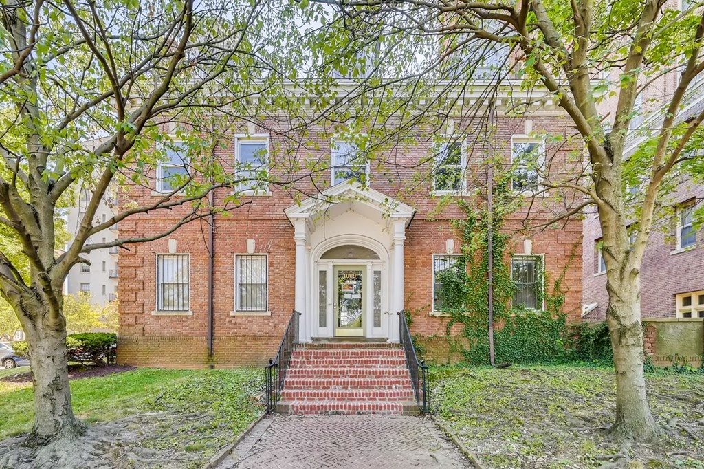A red brick house with a white door and steps leading up to it.