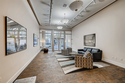 A living room with a black couch and a large painting on the wall.