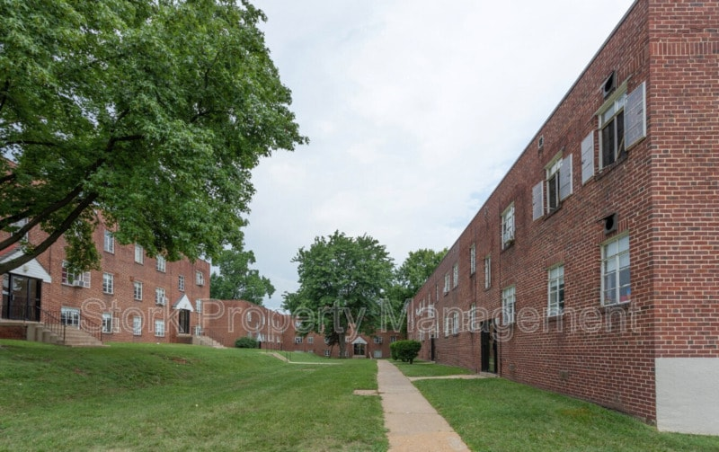 an exterior view of two brick buildings with grass and trees